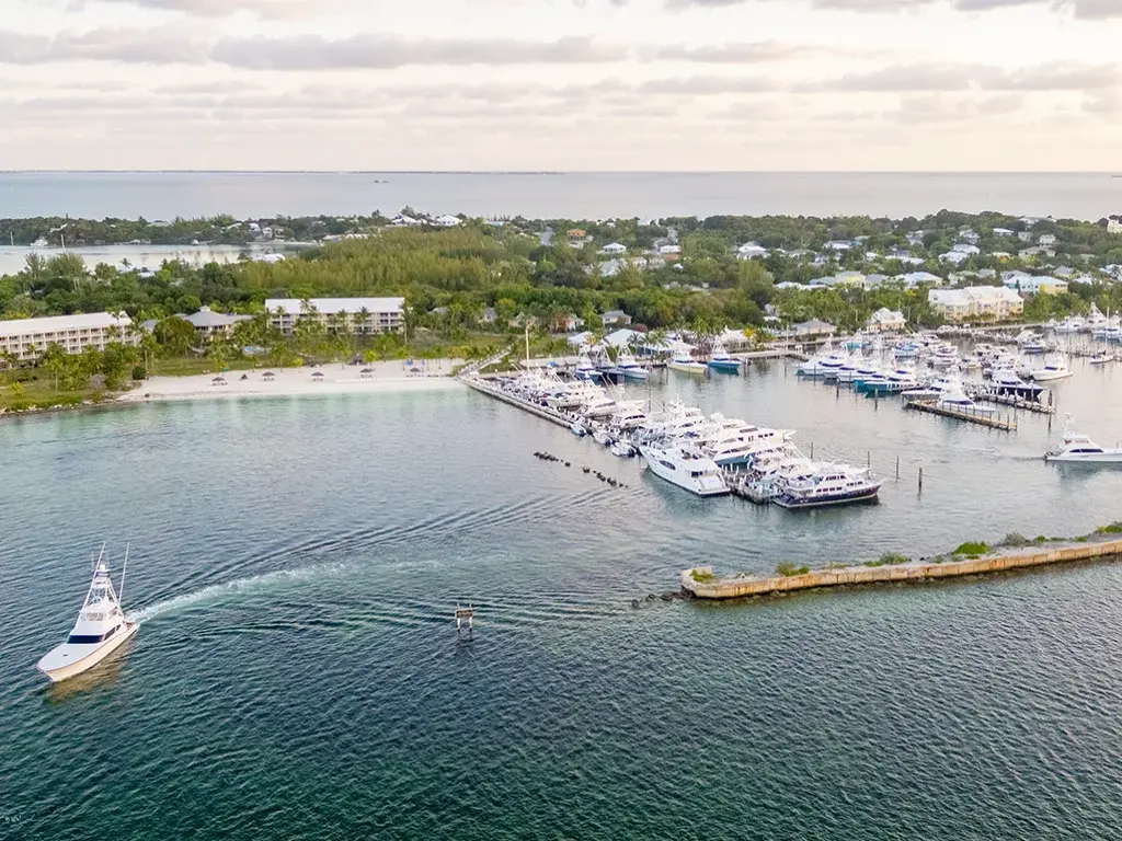 An aerial view of a marina, with a sportfishing boat leaving the channel.