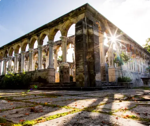 Stone arches of The Cloisters on Paradise Island, with sunlight between the columns.