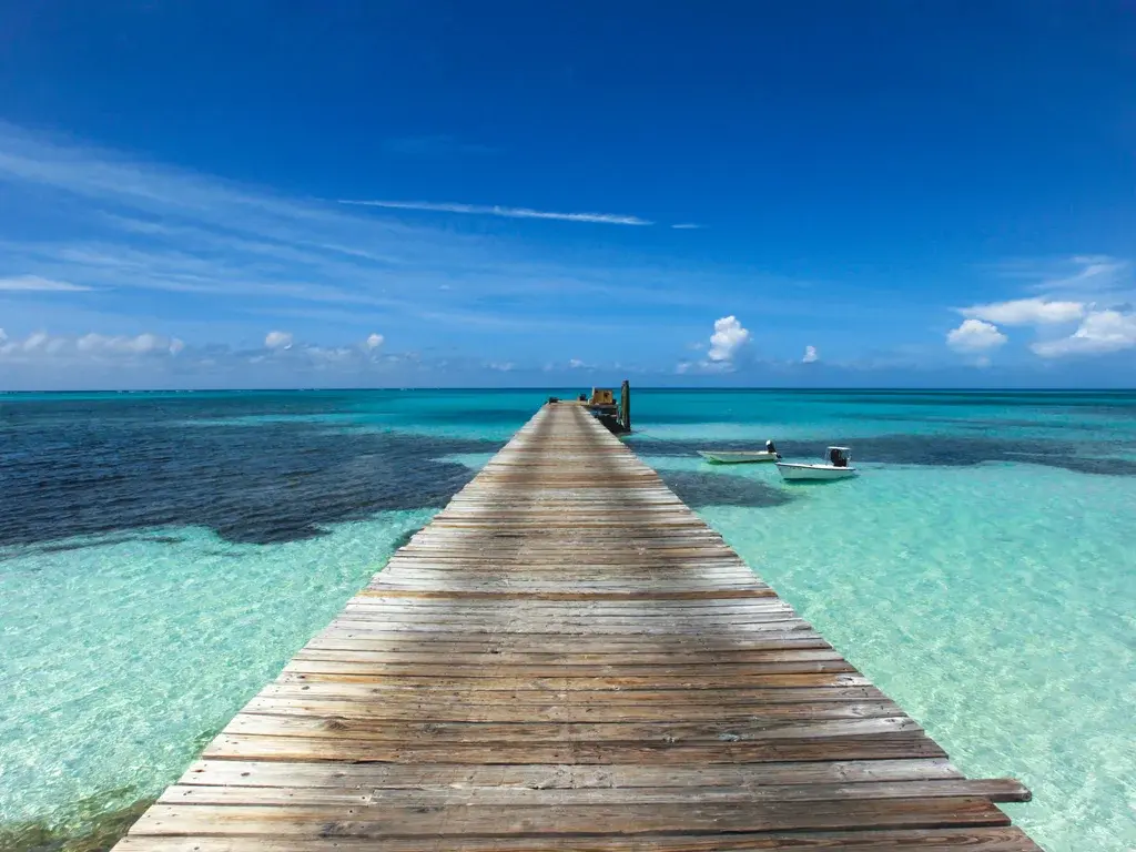 A long wooden dock runs into clear turquoise water at Rum Cay.