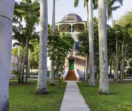 A path across a lawn leads to the octagonal domed library between royal palms.